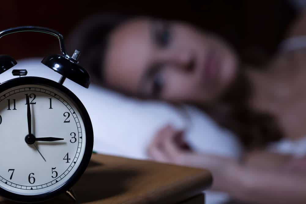 אישה שמתקשה לישון וצופה בשעון