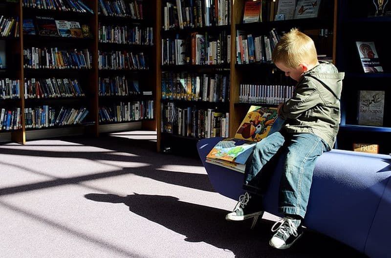 ילד קורא ספר לבד בספריה